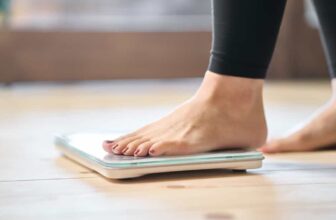 Woman weighing herself on a scale while tracking progress on how to lose 10 pounds in 2 weeks without exercise