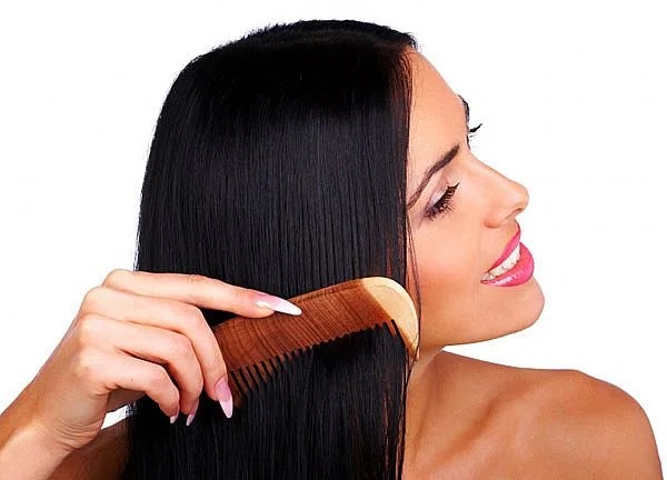 Woman gently combing her hair as part of routine showing how to take care of dry hair naturally
